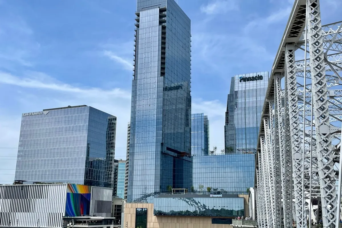 Four Seasons Hotel Nashville glass tower rising above city skyline with historic bridge truss in foreground