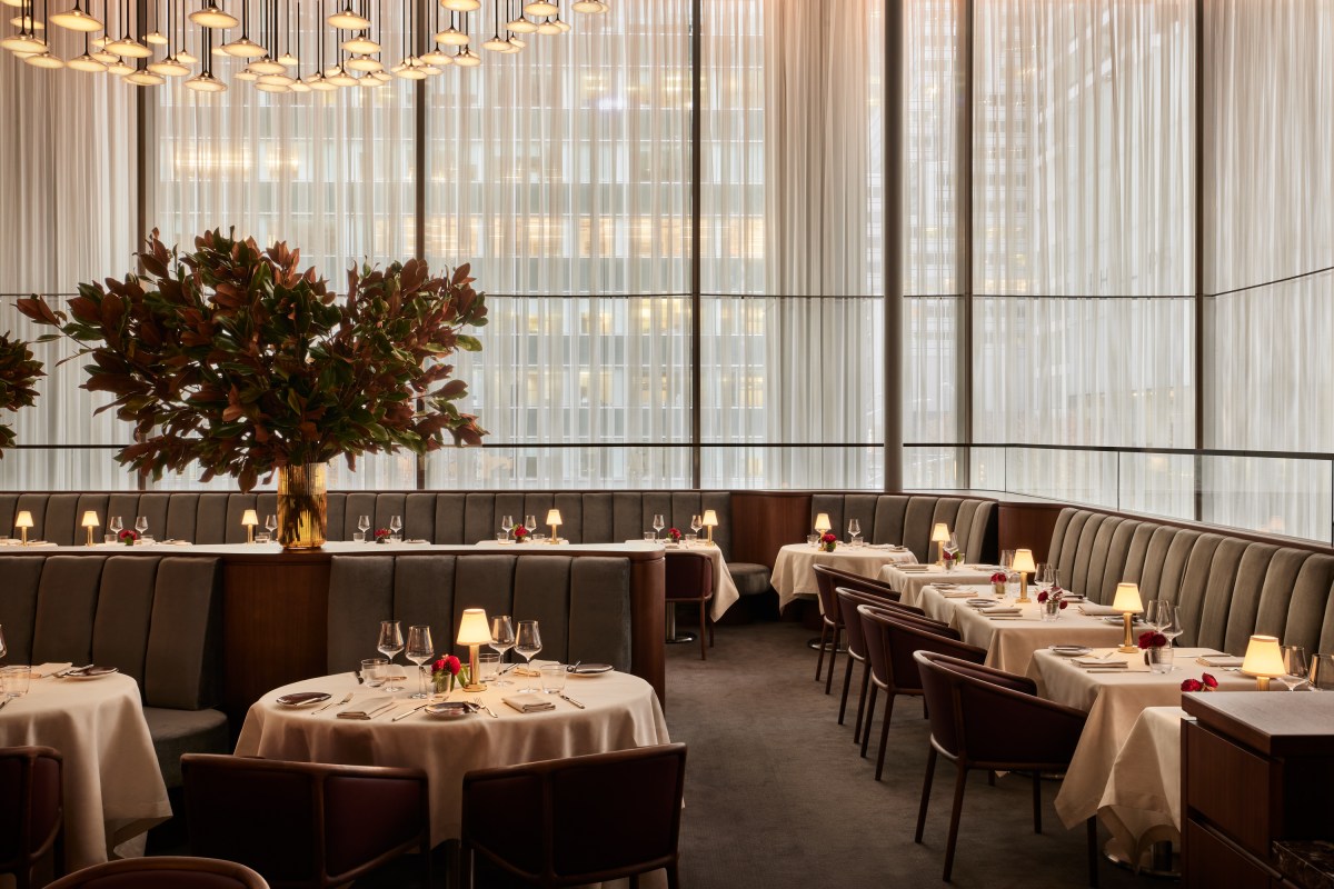 Spacious dining room with banquette seating, floral centerpieces, and floor-to-ceiling sheer curtained windows.