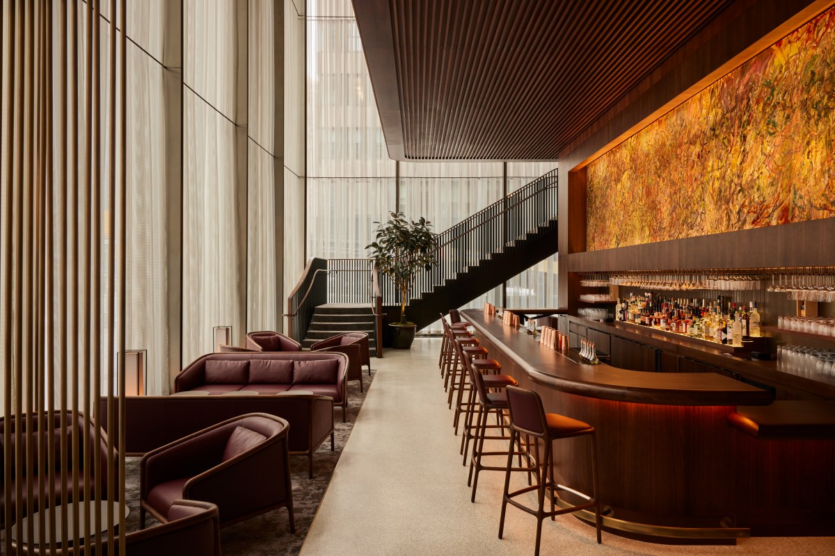 Modern lounge and bar area with leather armchairs, a staircase, and a large abstract artwork.
