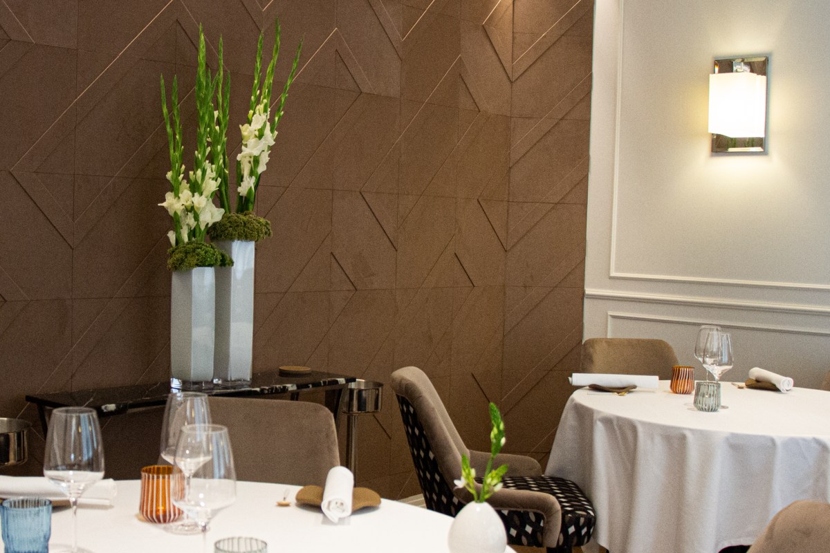 Elegant dining room with set tables, white florals, and warm brown paneled wall