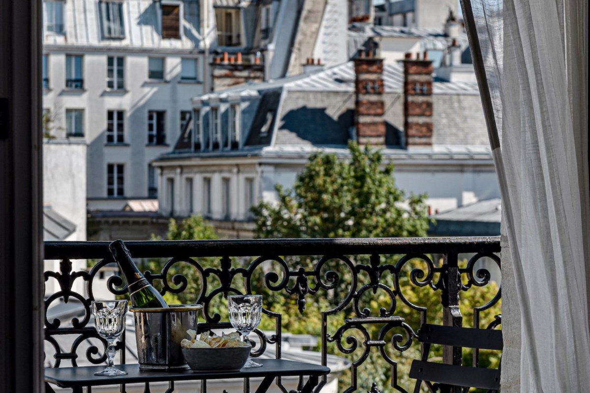 Paris rooftop view from a balcony with wrought-iron railing, wine glasses and champagne bucket