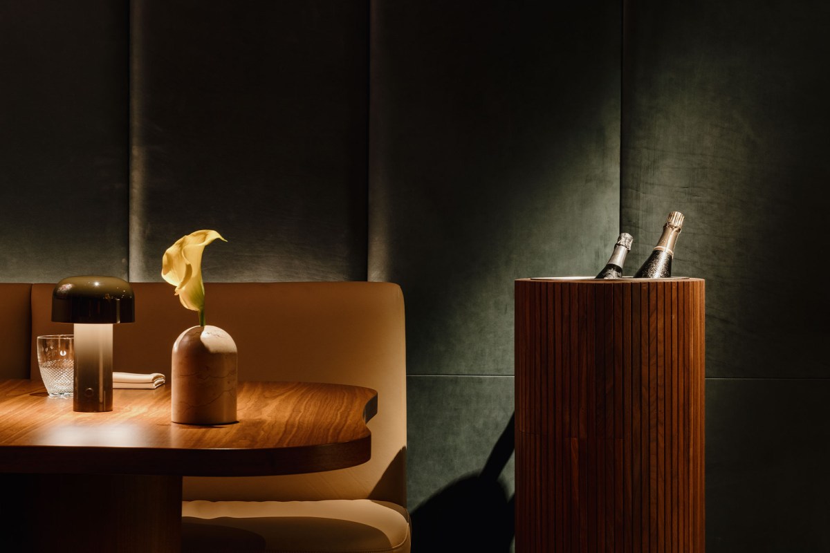 Moody dining room corner with wooden table, lamp, flower vase and champagne bottles chilling in a wooden ice bucket
