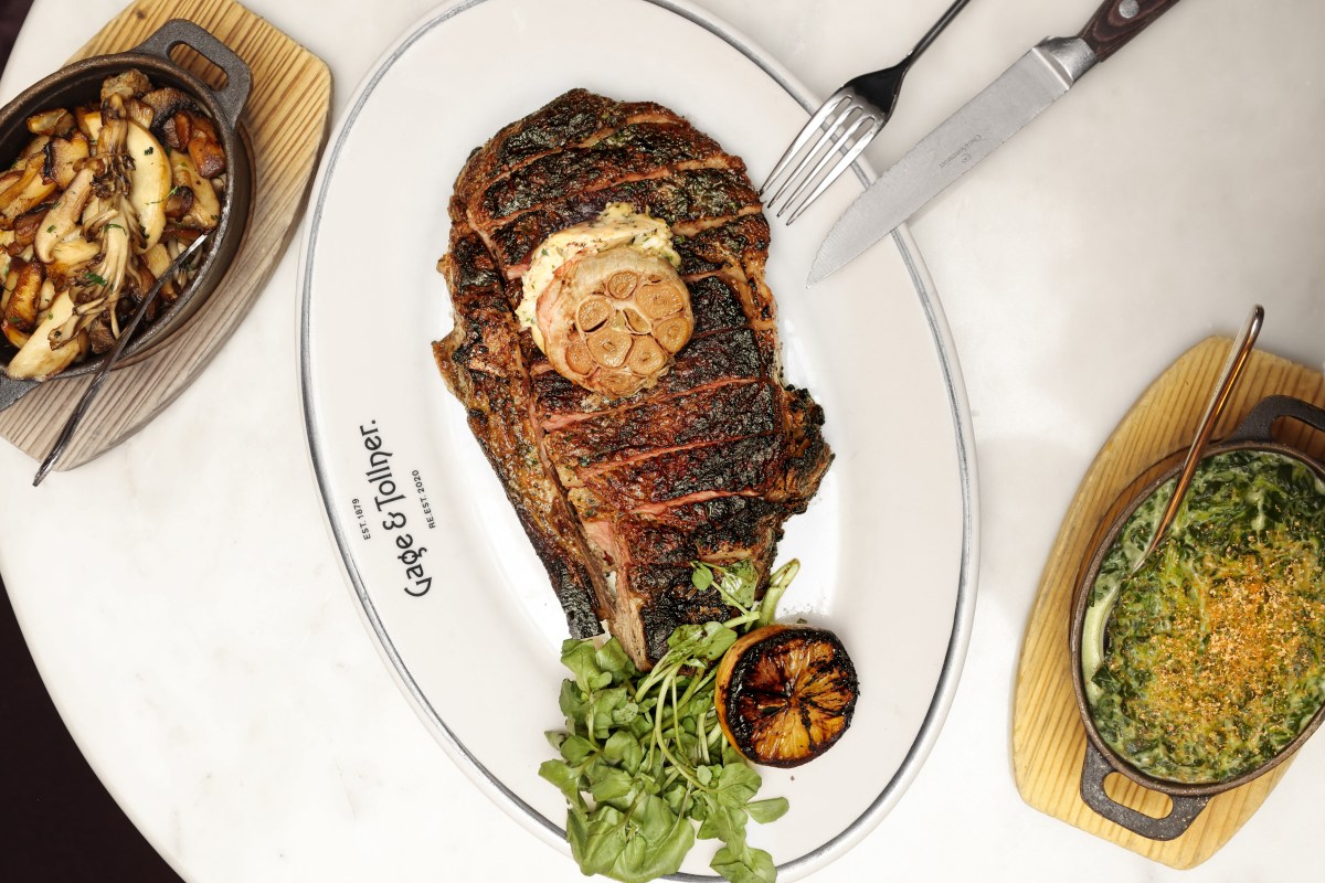 Grilled bone-in steak with garlic, lemon, and herbs on a branded Gage & Tollner plate, with mushroom and creamed greens sides.