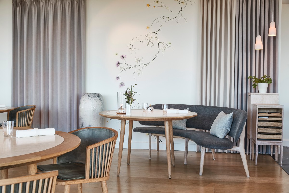 Cozy dining nook with round table, banquette seating and floral wall art