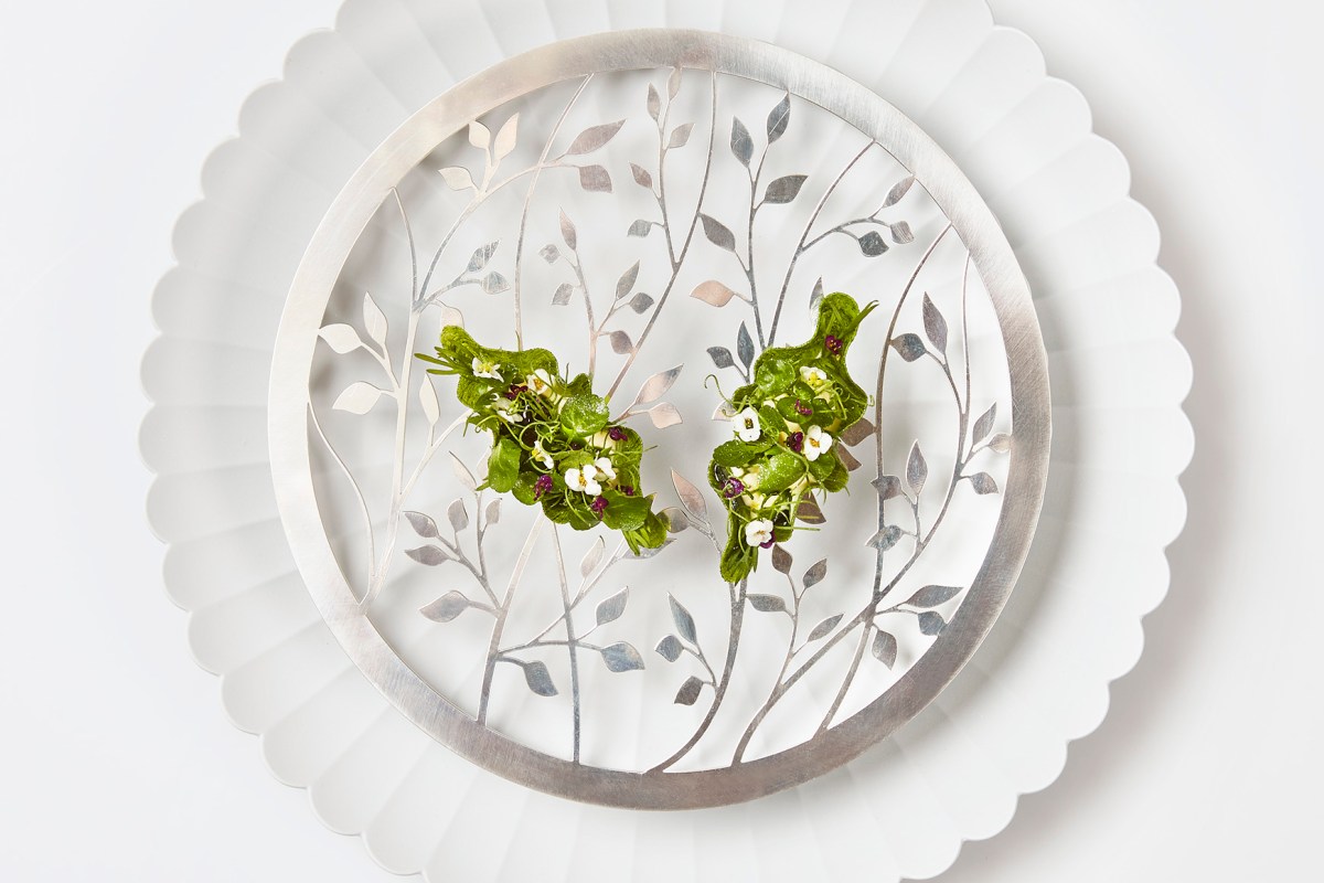Artfully plated green herb and flower dish on a decorative silver and white plate