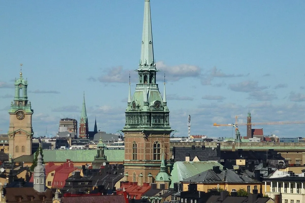 The copper-green spire of the German Church rising above the rooftops of Gamla stan in Stockholm, with Storkyrkan's tower to the left