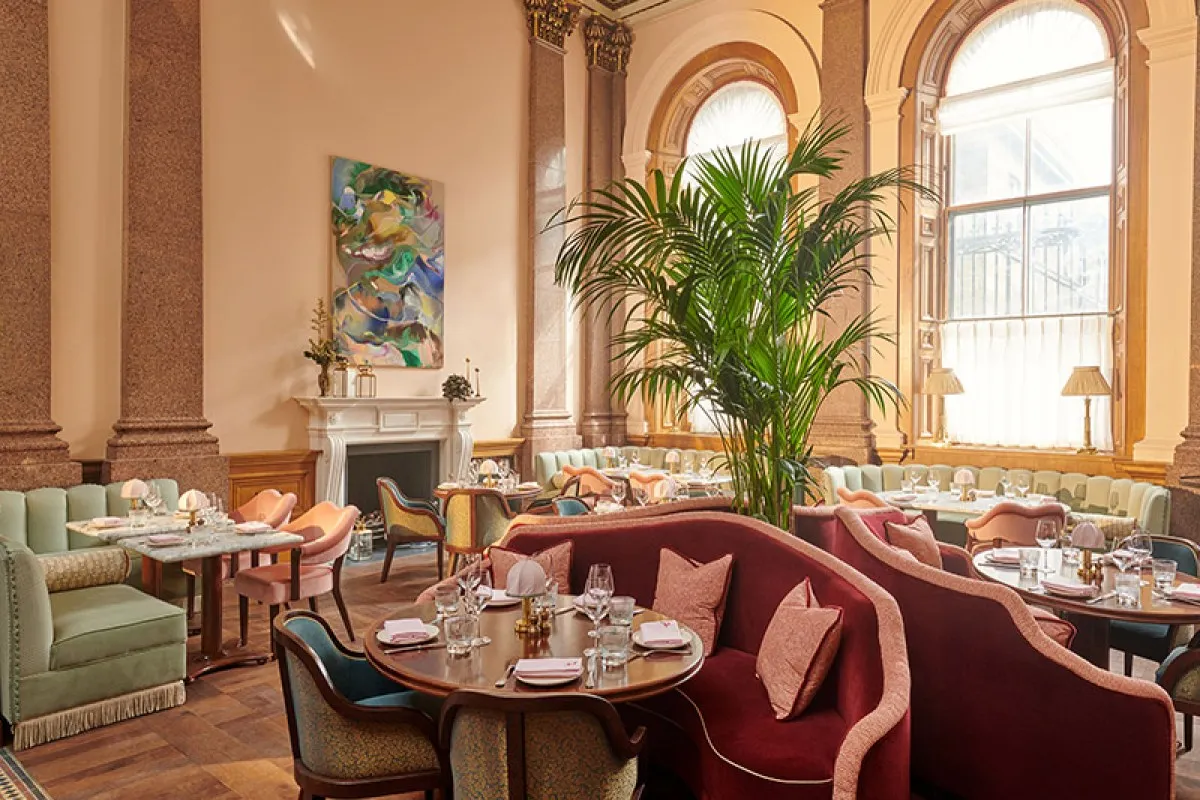 Elegant hotel restaurant with high windows, marble pillars, velvet booths and dining tables set for service