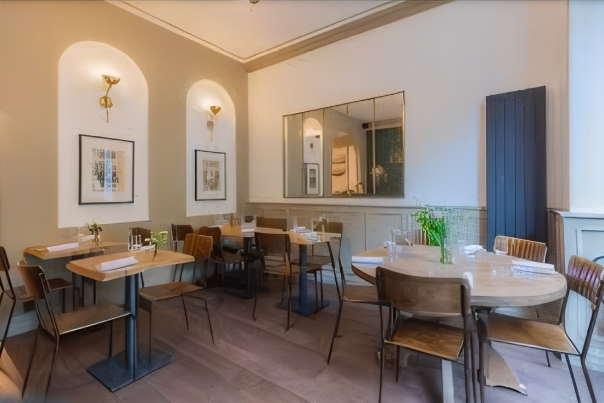 Restaurant dining room with arched wall niches, mirror, and several set tables