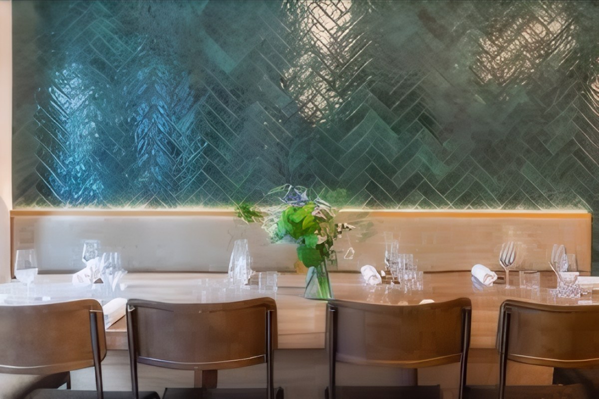 Close-up of a laid table with wine glasses and napkins against a green herringbone tiled wall