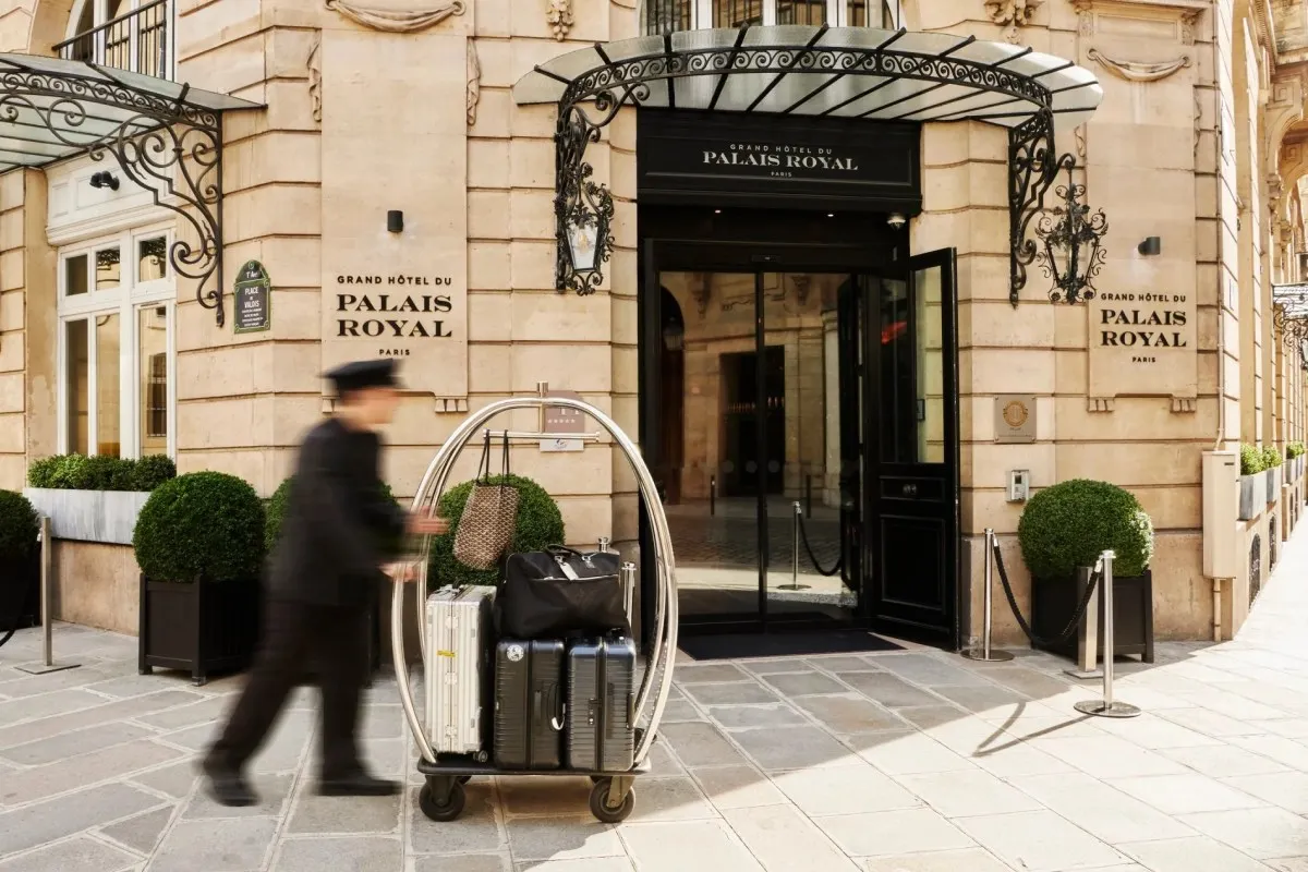 Hotel entrance facade with doorman, luggage cart, and Grand Hôtel du Palais Royal signage