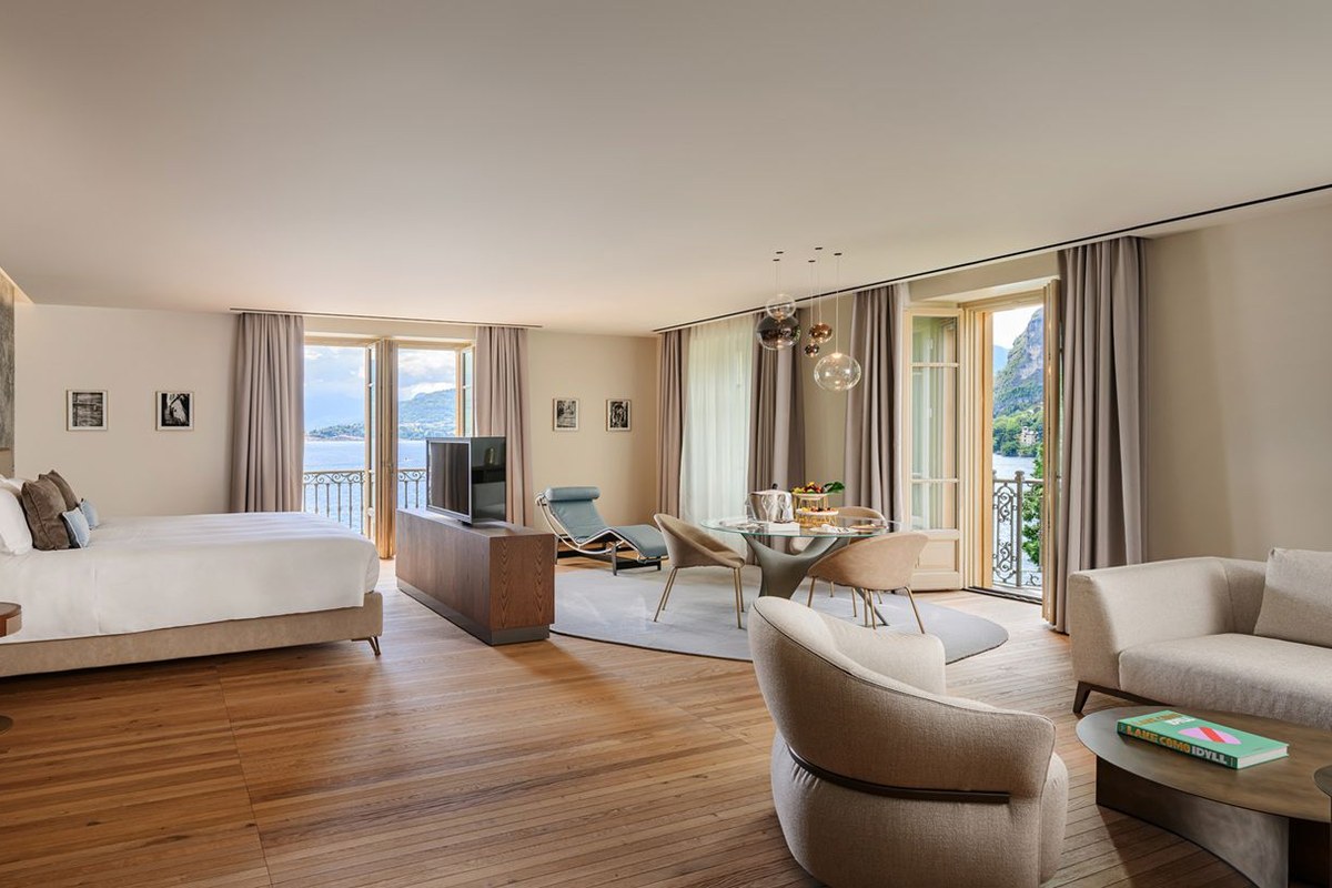 Spacious suite with king bed, seating area, wood floors and lake-view balconies