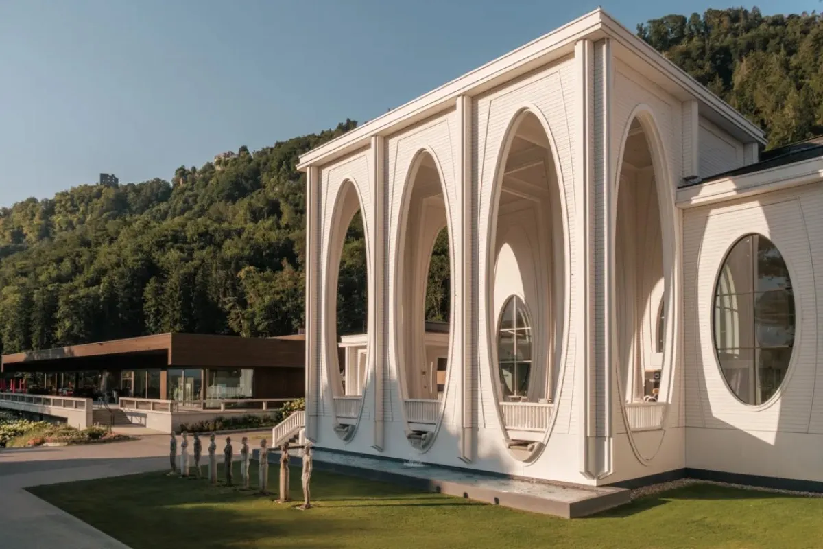 Modern white building with oval arched windows against a forested hillside at Grand Resort Bad Ragaz