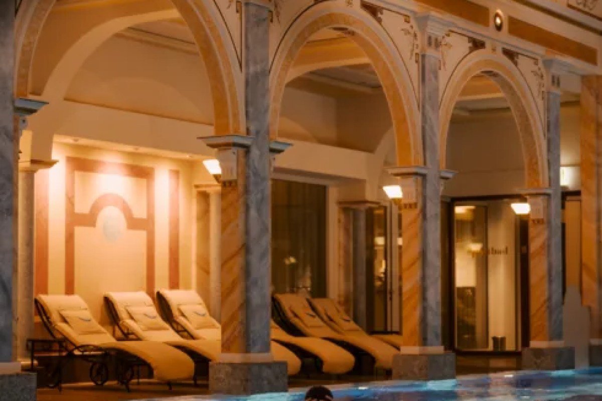 Indoor spa pool area with arched columns and loungers, evening lighting