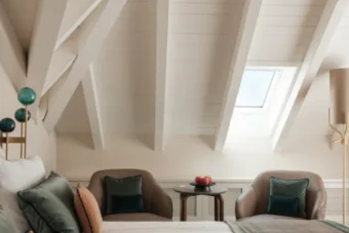 Attic-style guest room with sloped ceiling, skylight, and armchairs