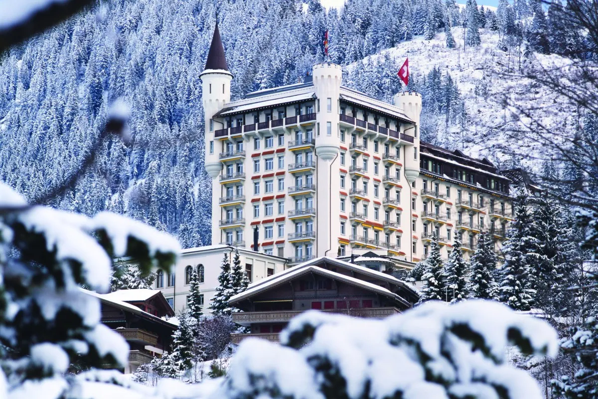 The turreted façade of the Gstaad Palace above snow-covered firs in winter