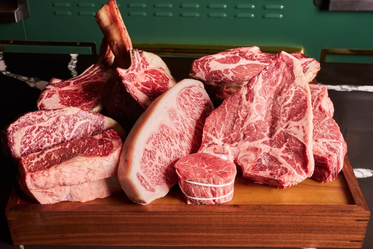 Assortment of raw marbled steaks and cuts displayed on a wooden board