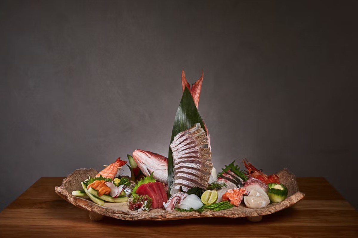 Elaborate sashimi platter with whole fish, shrimp, and assorted seafood on stone plate