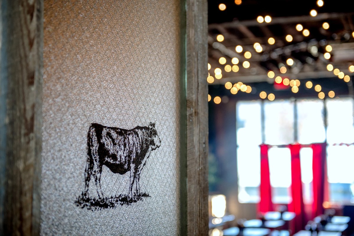 Interior dining room view with string lights, red curtains, and cow motif decor