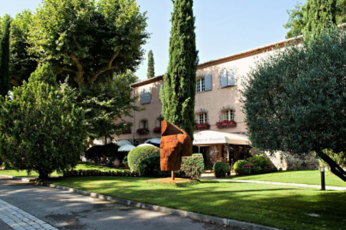 Provençal-style hotel exterior with cypress trees, garden and terrace entrance