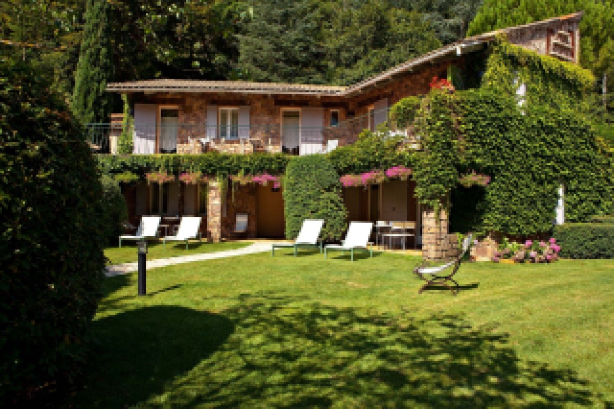 Stone hotel building covered in ivy with garden and lounge chairs, alternate angle