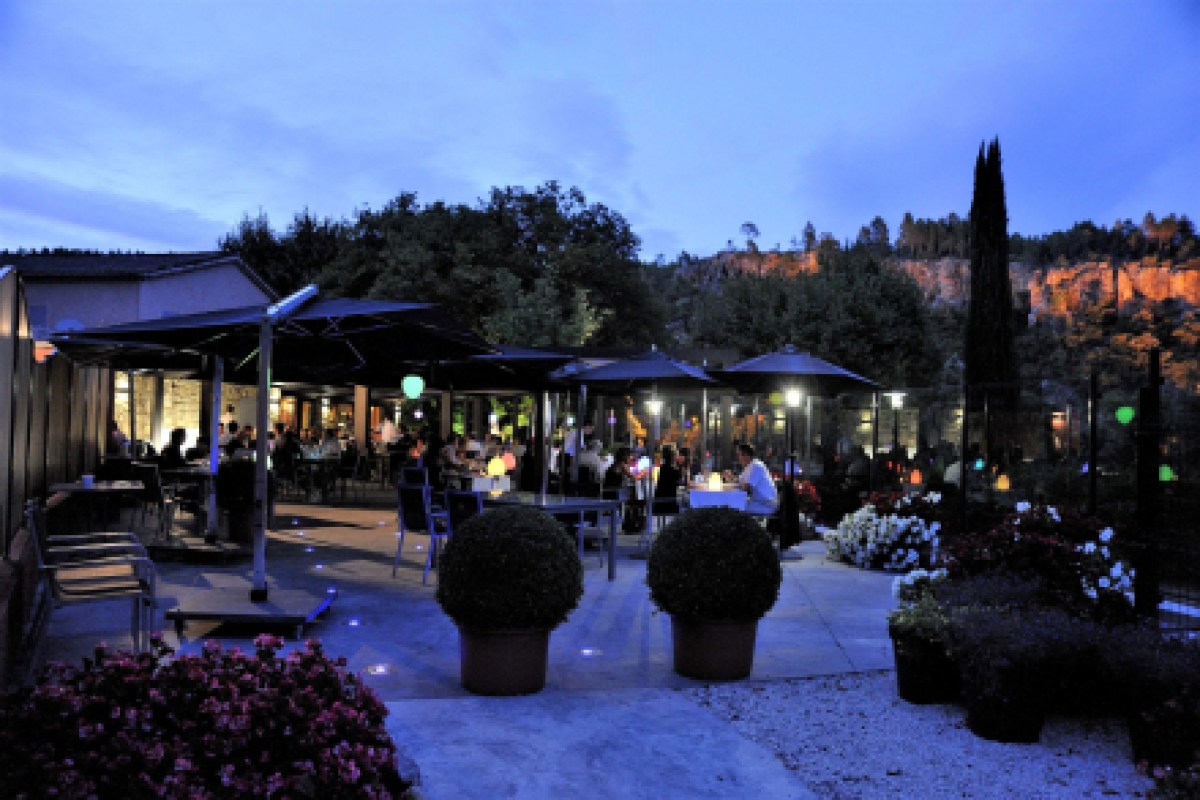 Outdoor restaurant terrace at dusk with diners and gorge backdrop