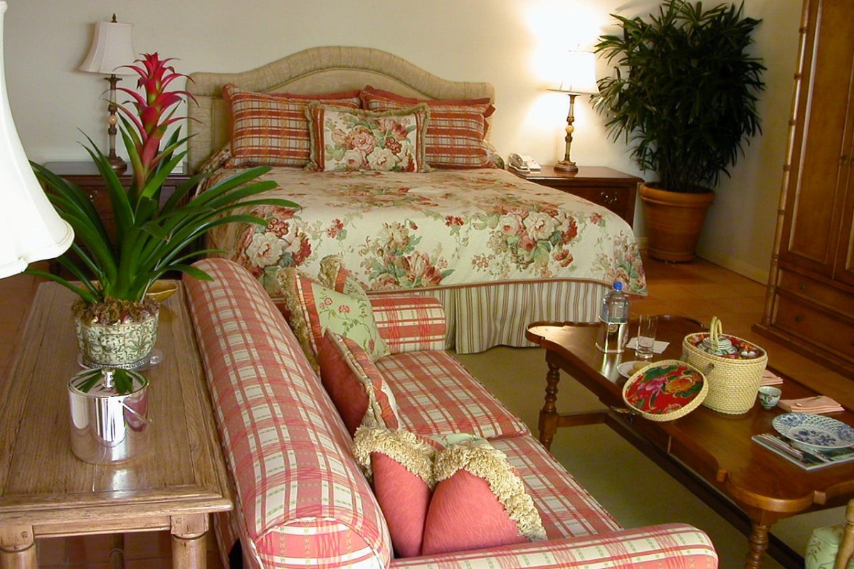 Elegant guest room with floral bedding, plaid sofa, and wooden furniture