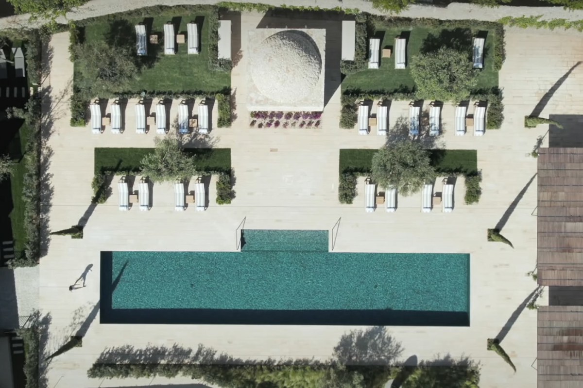 Aerial view of the hotel's pool, terrace and sun loungers with part of the building visible at the edge