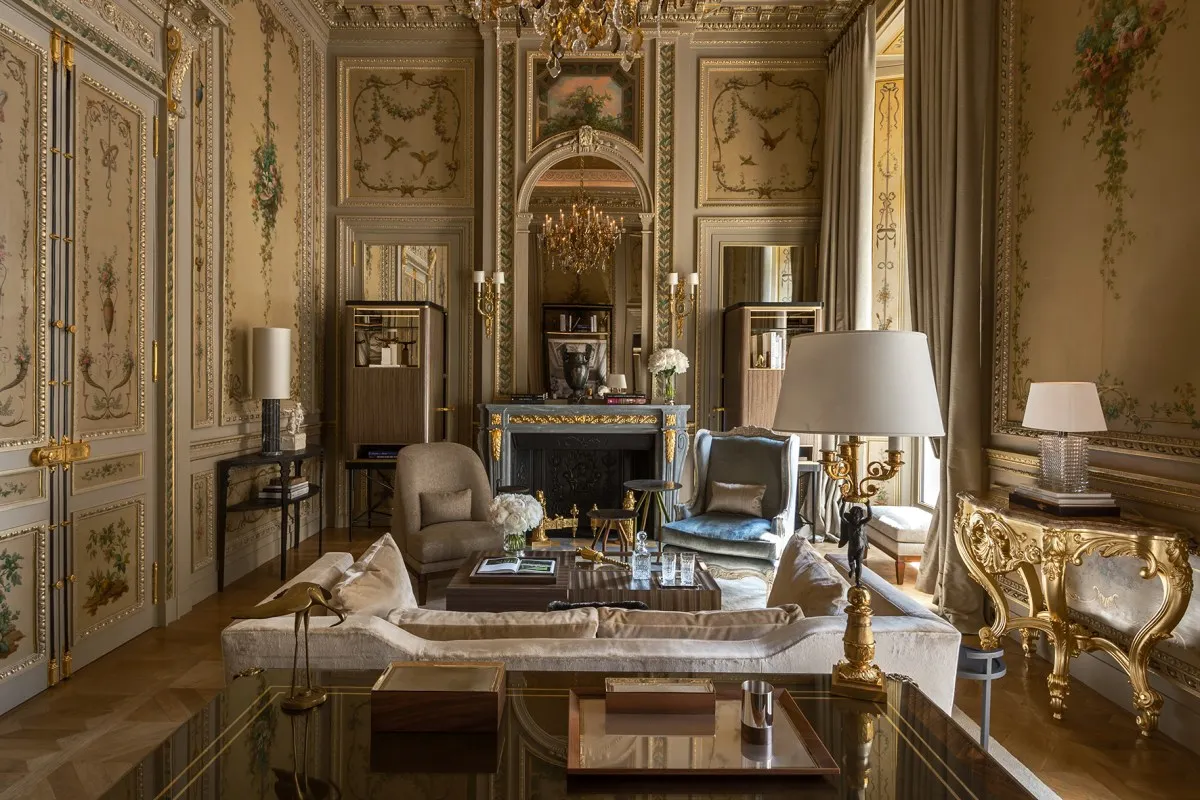 Opulent suite living room with painted panelled walls, chandelier, fireplace and gilded furniture