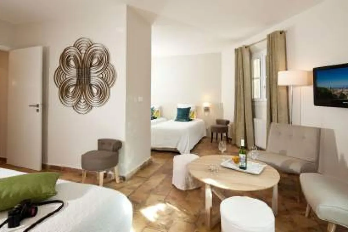 Hotel suite with twin beds, seating area, round table and decorative wall art