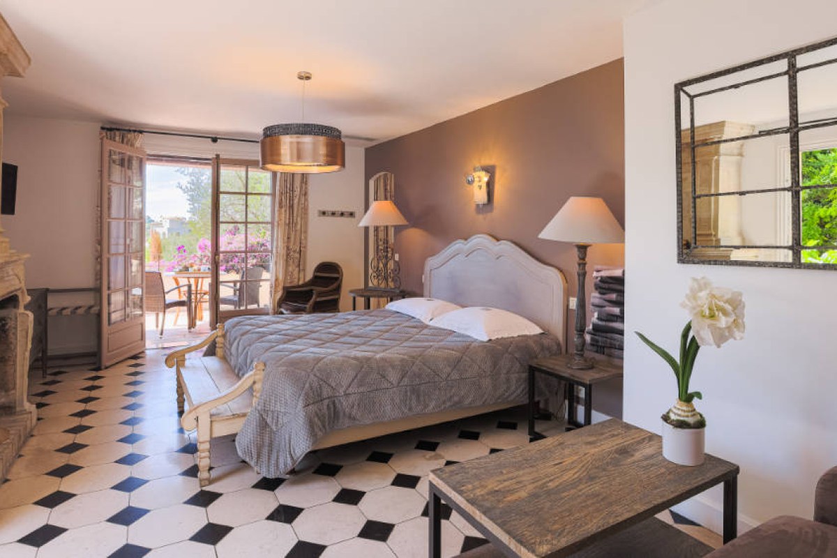 Elegant guest room with checkered floor, large bed, and French doors opening to a terrace
