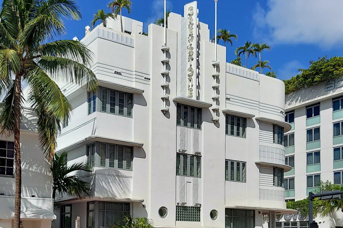 Art Deco Greystone Hotel exterior in Miami Beach with palm trees against blue sky