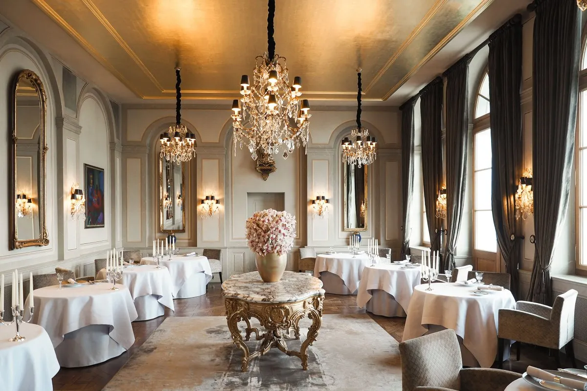 Elegant hotel restaurant with gold ceiling, crystal chandeliers and white-clothed tables