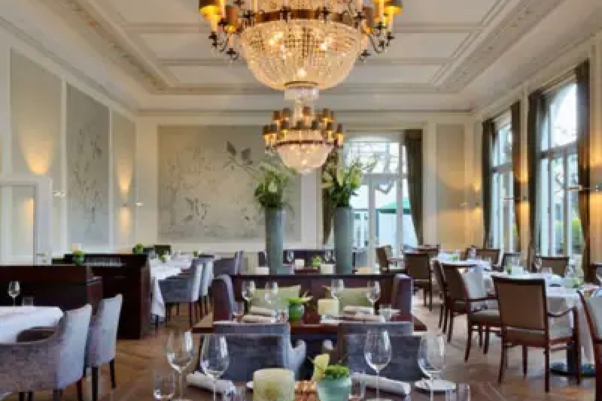 Elegant hotel restaurant with chandeliers, white tablecloths and tall windows
