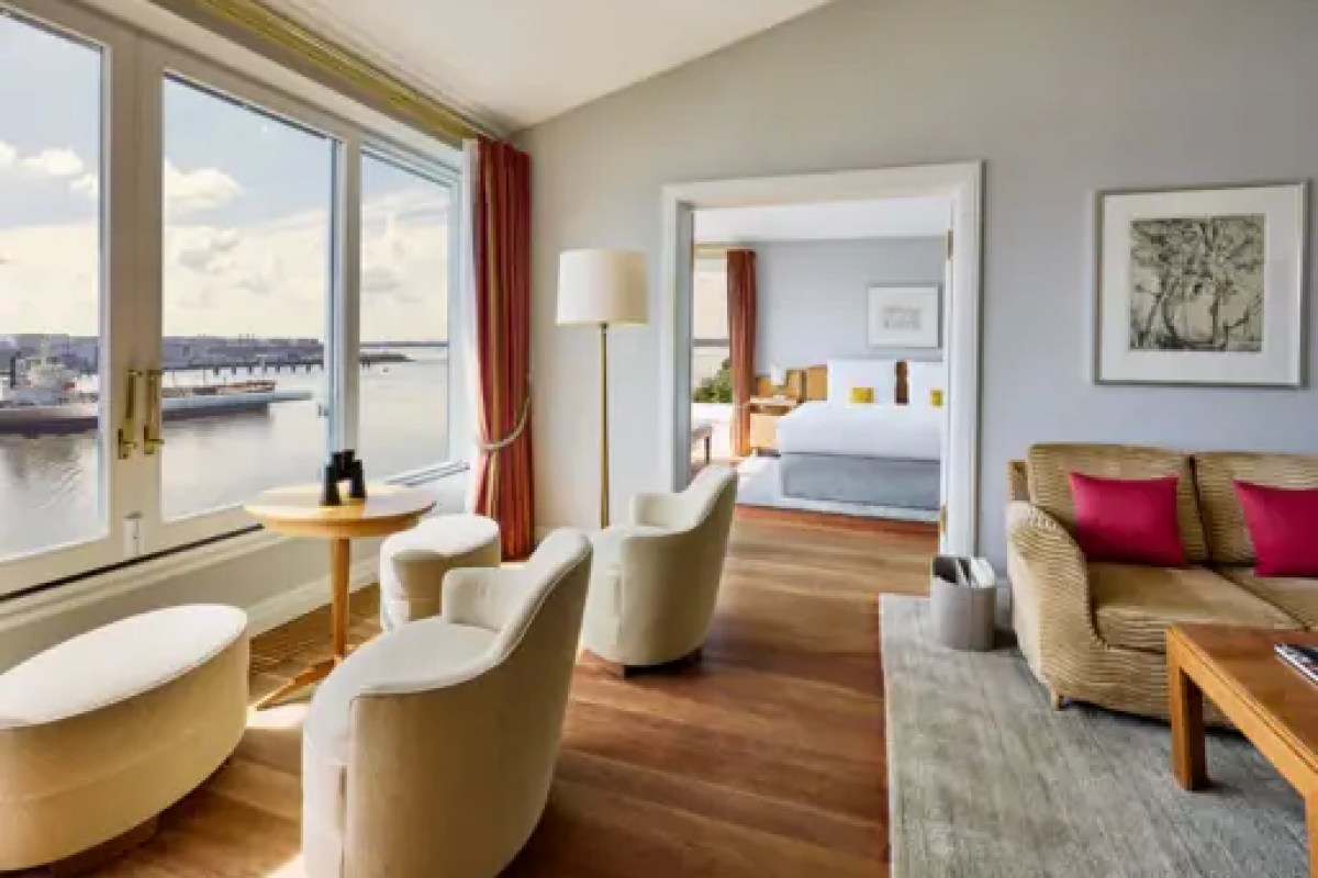 Hotel suite living room with harbor view, sofa and glimpse of bedroom beyond