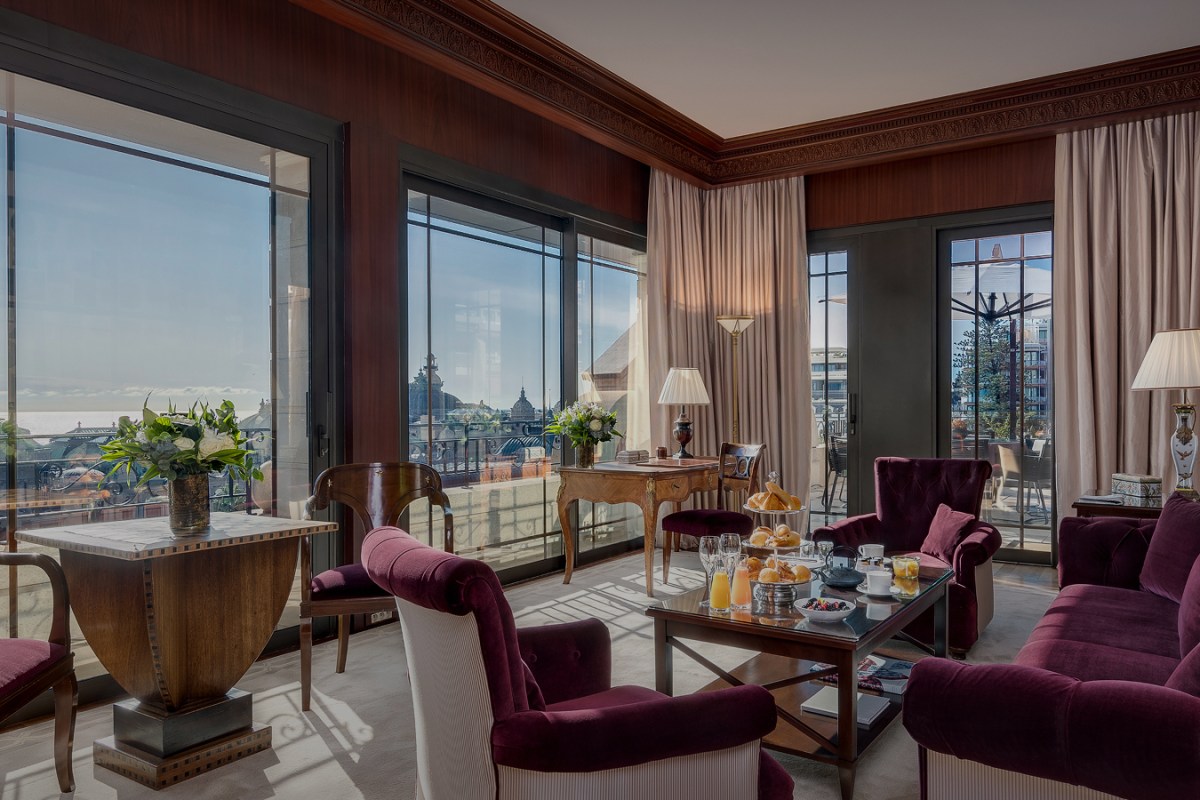 Suite living room with velvet armchairs, breakfast spread and panoramic city view