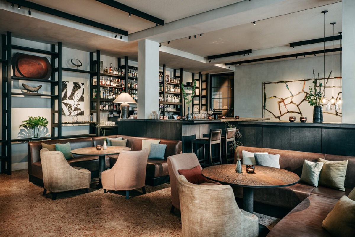 Hotel bar/lounge area with leather banquettes, armchairs, and shelved bottles