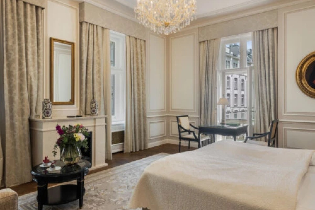 Classic hotel bedroom with crystal chandelier, fireplace, fresh flowers and city view