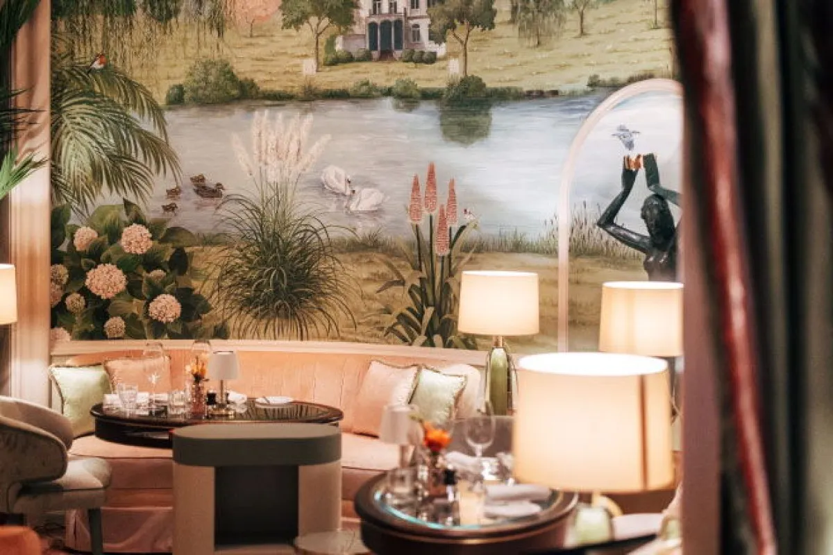 Elegant lounge seating area with mural wallpaper of a lake scene and lamps