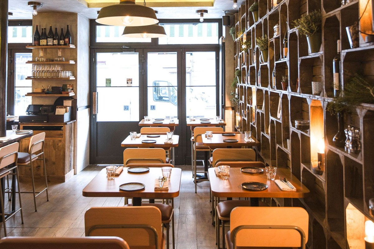 Interior dining room of Hugo & Co with wooden tables, crate shelving, and view toward entrance