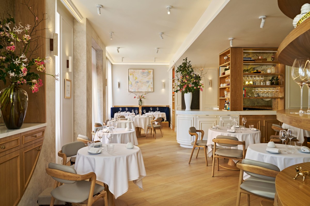 Wide view of restaurant dining room with wooden tables, chairs, and bar area