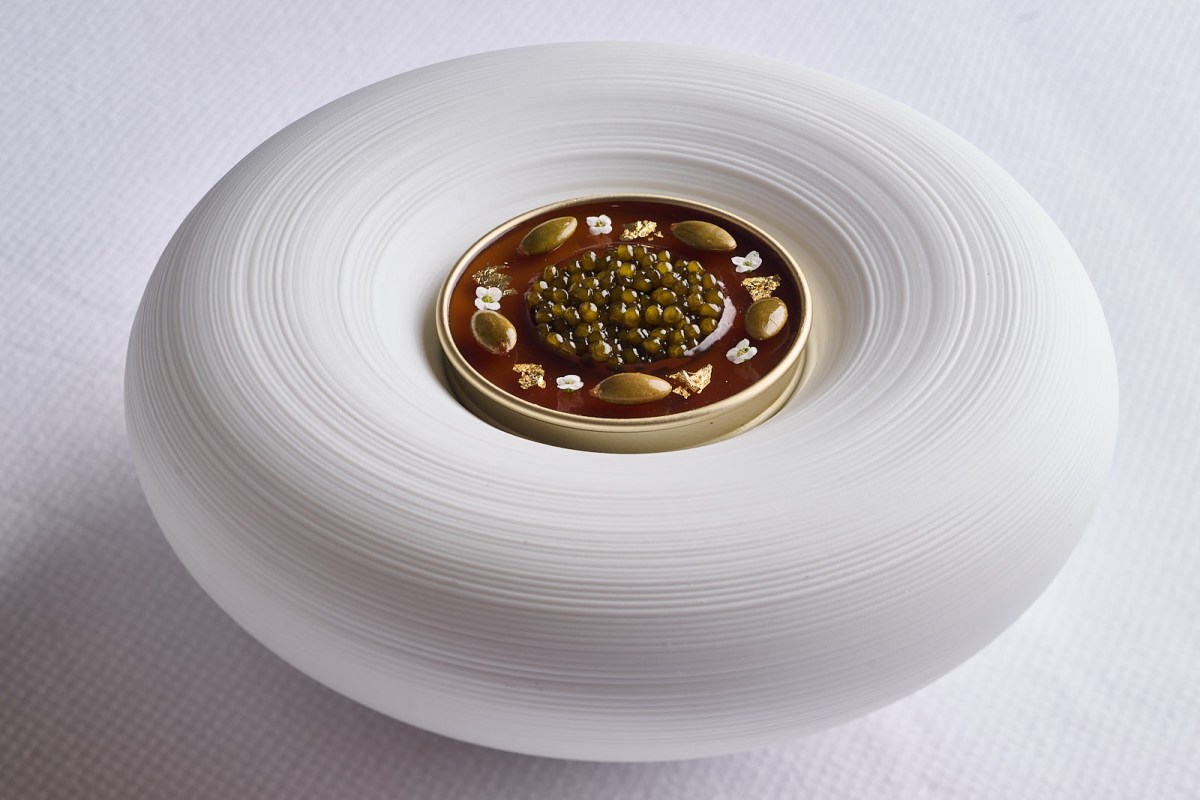 Close-up of a caviar dish served in a round white ceramic vessel