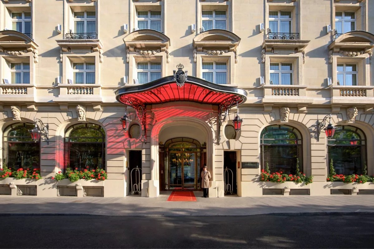 Hotel entrance facade with red canopy and flower boxes on a Paris street