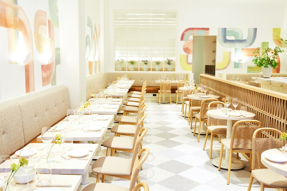 Bright dining room with checkered floor, banquette seating, rattan chairs and colorful abstract wall art