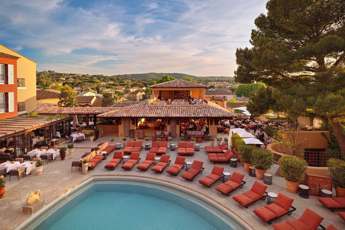 Wide aerial view of Il Giardino pool terrace, striped dining tables, lounge chairs and rooftop bar with town view
