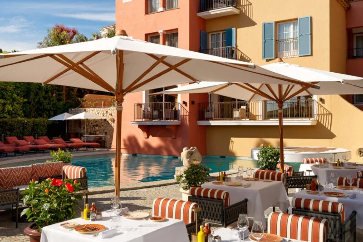 Poolside dining terrace at Il Giardino with laid white-clothed tables, striped chairs and large umbrellas beside the pool