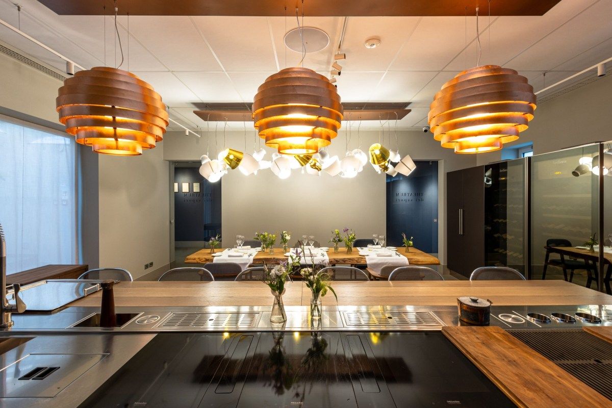Modern dining room with large copper pendant lamps over a kitchen counter and set dining table in the background