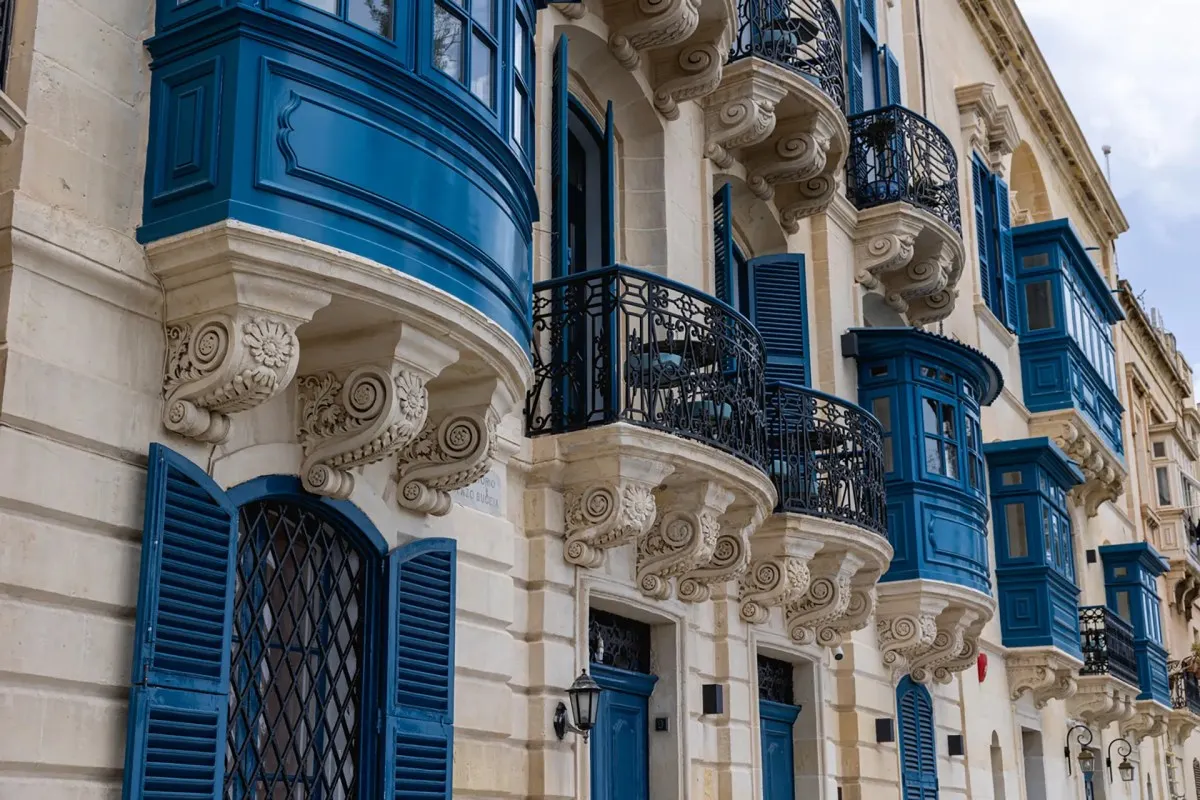 Traditional Maltese stone building façade with ornate blue wooden balconies and shuttered windows in Valletta