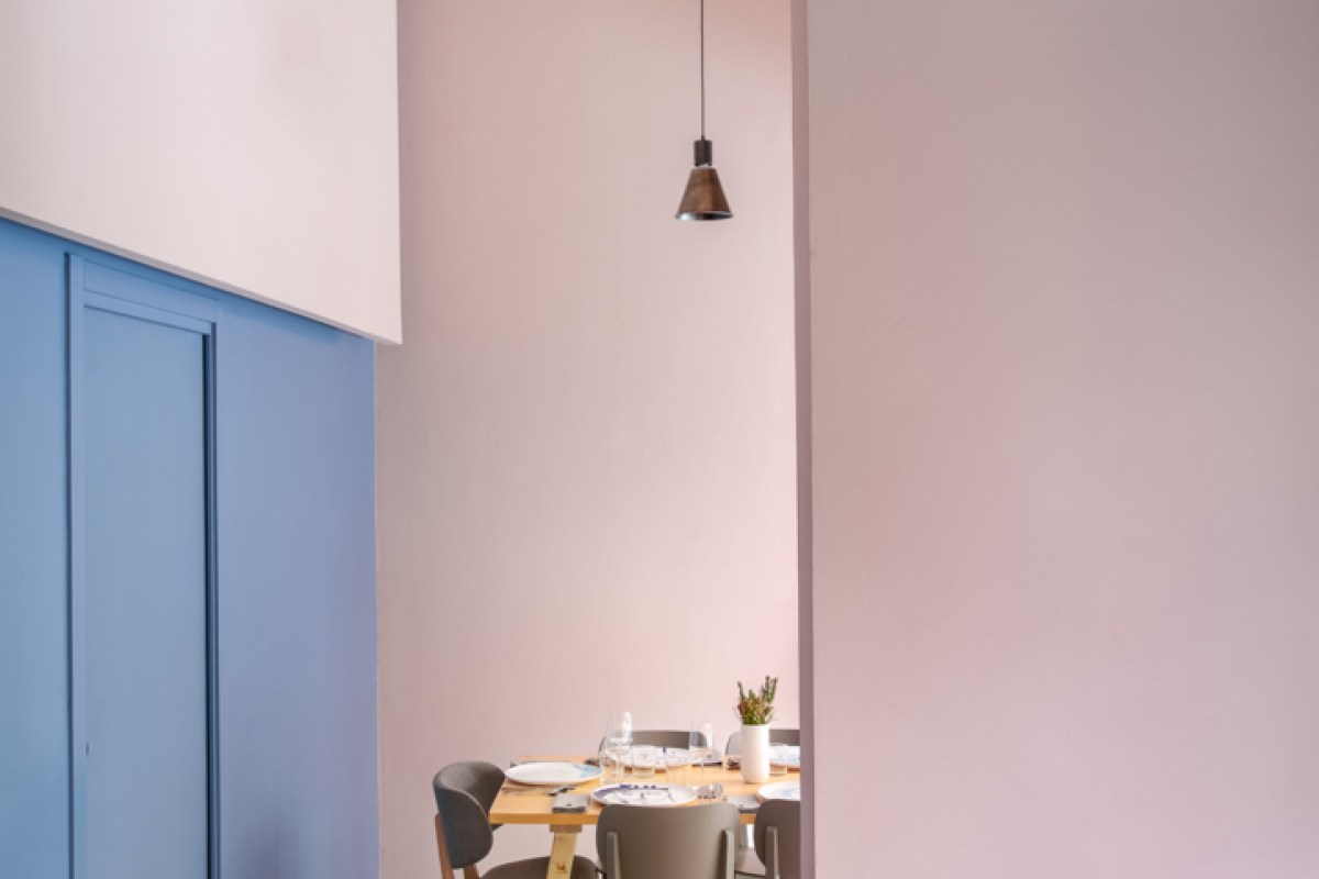 Pink and blue dining room corner with a hanging pendant light and set table in the background
