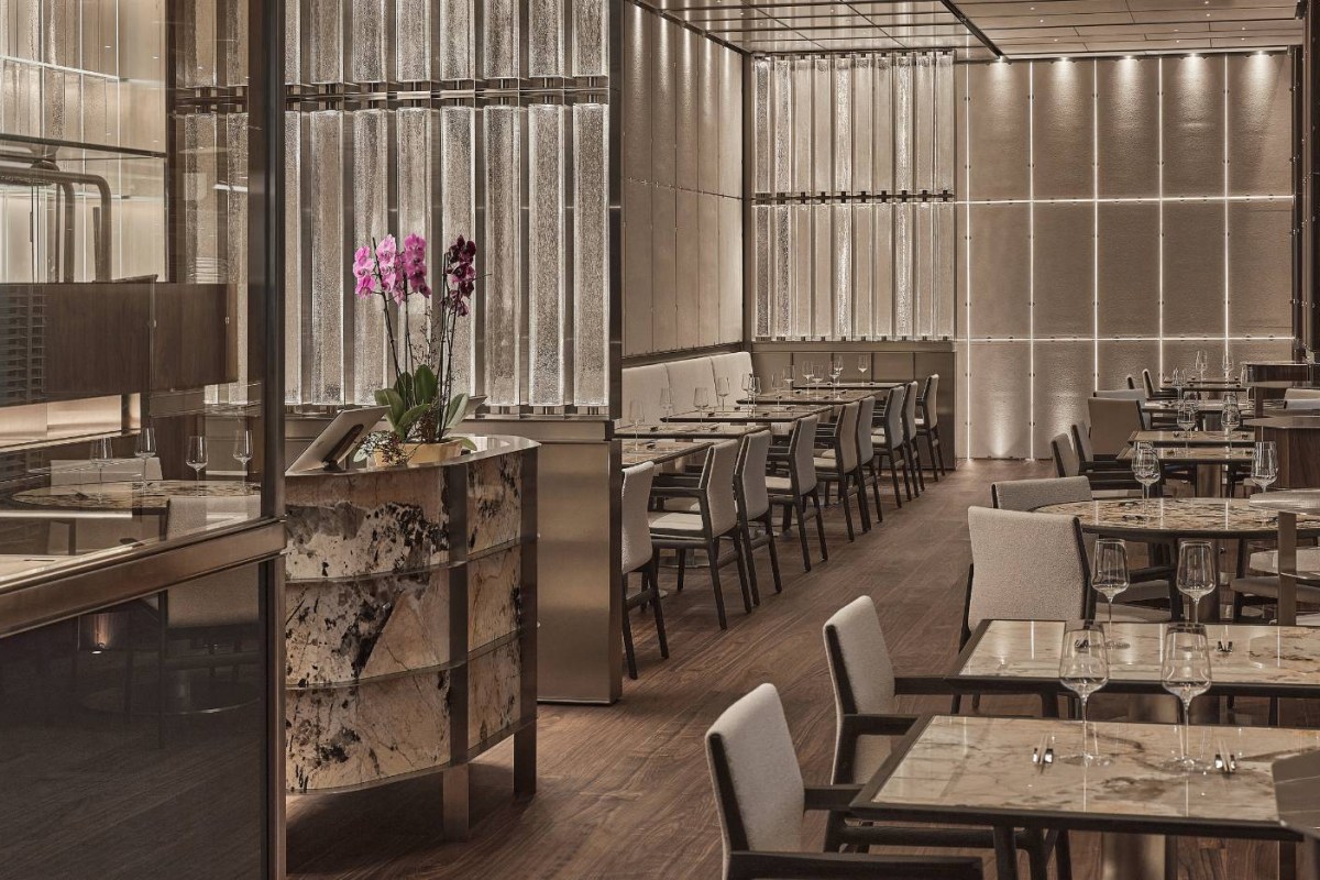 Elegant dining room with marble tables, upholstered chairs and backlit glass wall panels at IYO restaurant
