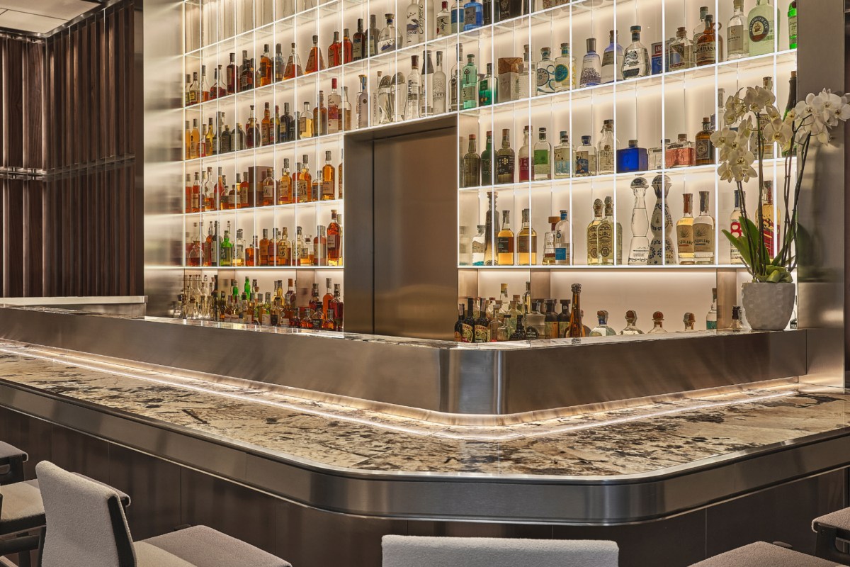 Sleek bar area with marble countertop and illuminated shelves of spirits at IYO restaurant